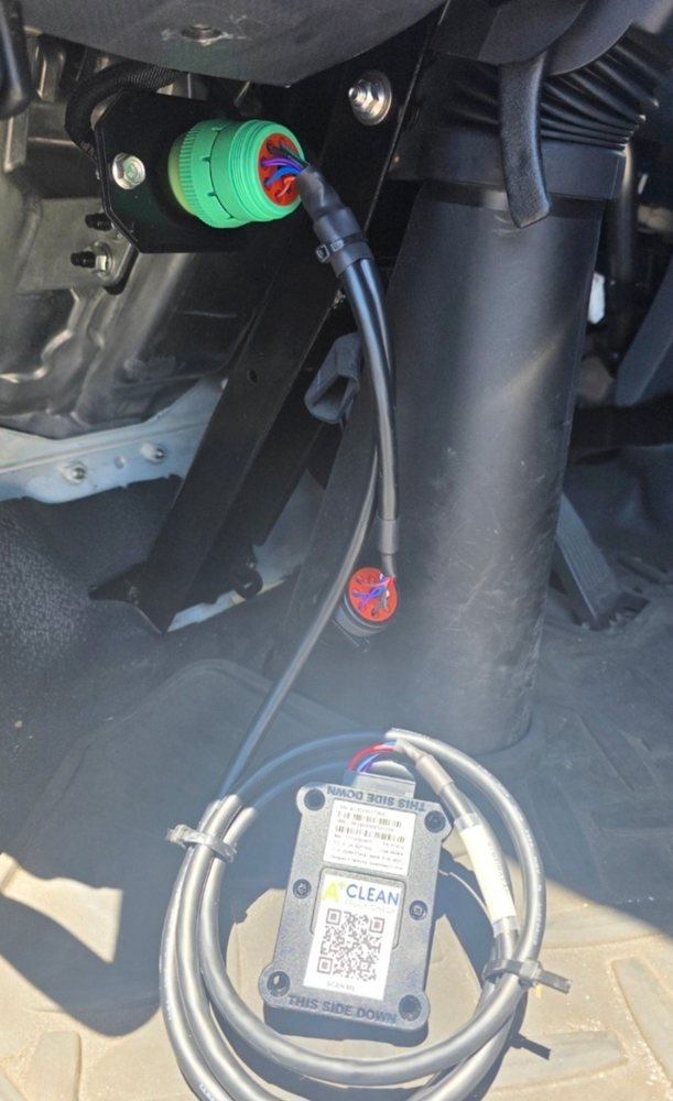 A CC40 installed in a truck cab, cable run from the green 9-pin diagnostic port down to the device, coiled and zip-tied clear of the pedals