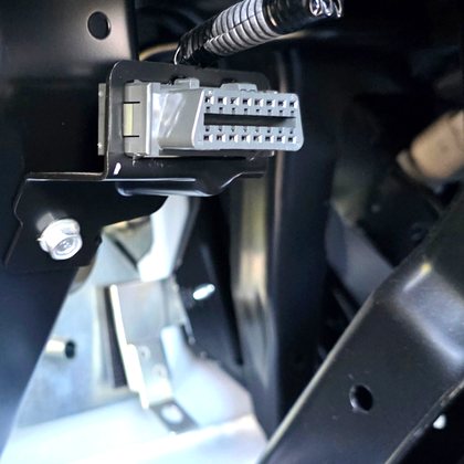 Grey 16-pin OBD-II diagnostic port mounted under a truck dash