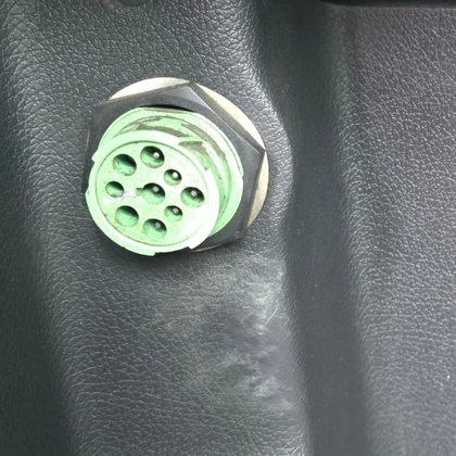 Round green 9-pin J1939 diagnostic port inside a truck cab